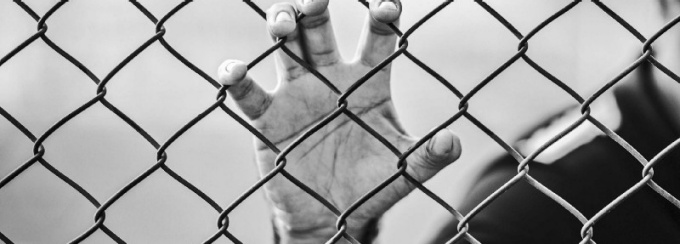 hand gripping chain link fence. 