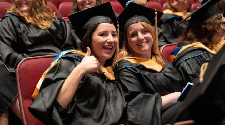 students giving thumbs up at commencement. 
