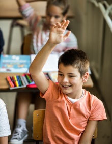 Young boy raising hand in class. 