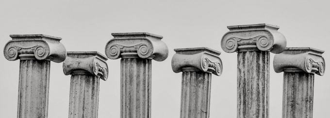 The top halves of 6 ancient pillars in greyscale. 