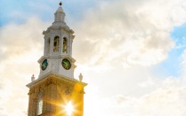 sun shining behind the clock tower on the south campus. 
