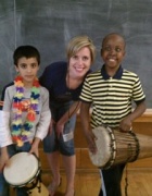 Adult standing with children holding drums. 
