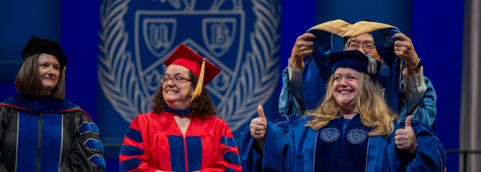 DSW graduate getting hooded on stage by Isok Kim.