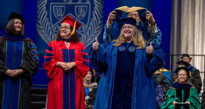 DSW graduate Missy giving thumbs-up onstage at commencement.