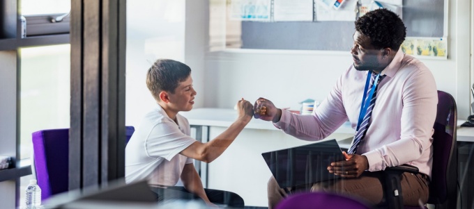 A school social worker fist bumps with a young student. 