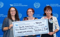 one student and faculty holding oversized check. 