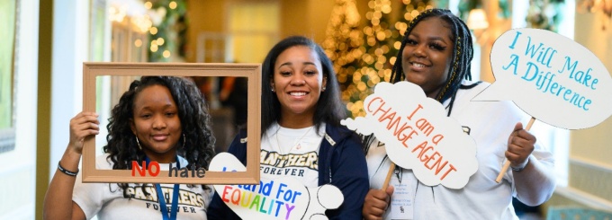 3 local high school students pose with props reading, "I am a change agent," "I will make a difference," and "I stand for equality.'. 
