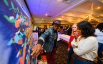 Zoom image: Edreys Wajed, a local artist, educator and musician, talks about a &quot;live&quot; painting he created with student attendees at the Challenge 2 Change summit. 