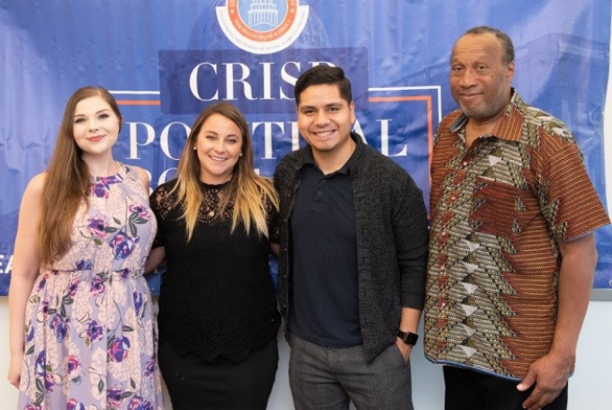 Whitney Marris, Kristen Hibit, Hector Chaidez Ruacho, and CRISP President Dr. Charles E. Lewis, Jr. pose in front of blue back-drop at CRISP Political Bootcamp and Media Training. 