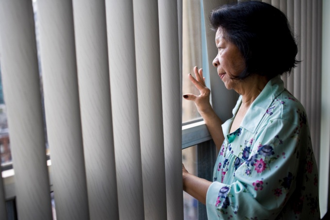 Elderly Asian woman looking out a window. 