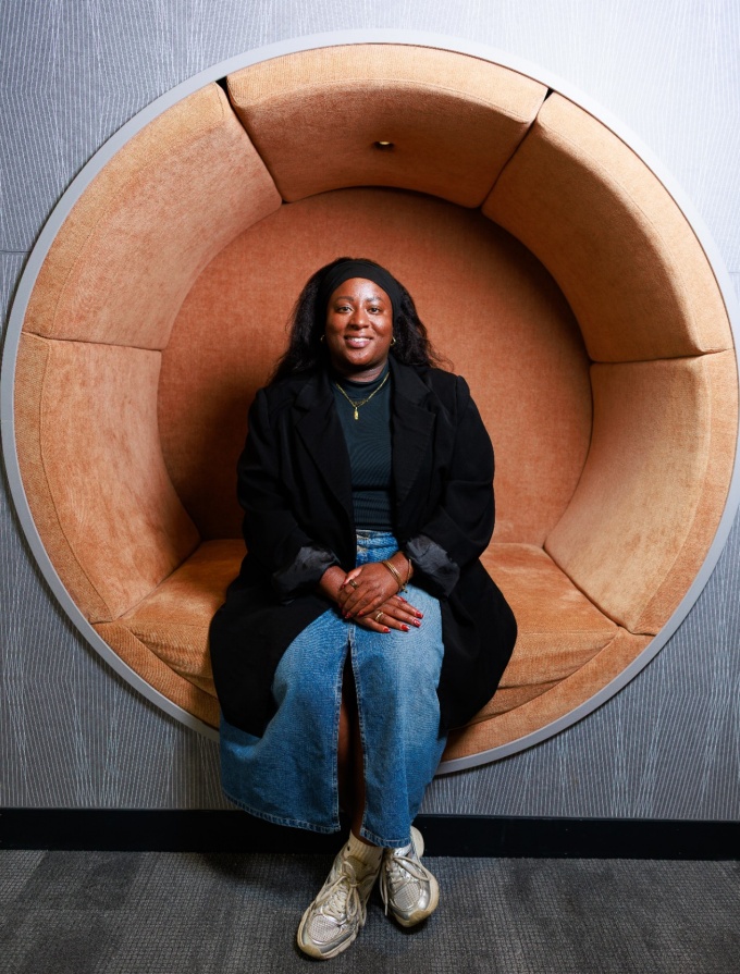 Rachel Eastlack sitting in a round chair mounted to a wall.