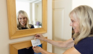 Zoom image: Cindy German placing a "donate" sign on a mirror.