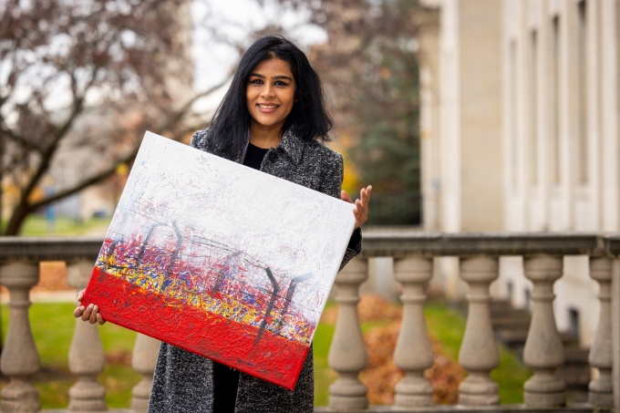 Shaanta Murshid holding a painting outside of Parker Hall. 