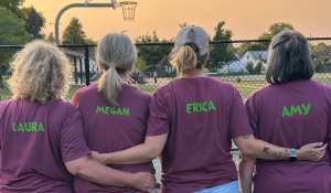 Amy Hicks and three friends, with their backs to the camera, each with their name on a matching T-shirt for pickleball. 