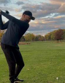 Alex Rubin swinging a golf club on a green. 