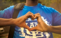 Person wearing a UB shirt making a heart symbol with their hands. 