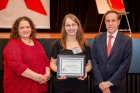 Zoom image: Samantha Koury pictured with two other individuals, one male and one female, from the NYS Department of Health. Samantha is holding the plaque for the Ken Dunning Trauma-Informed Care Award that she received. 